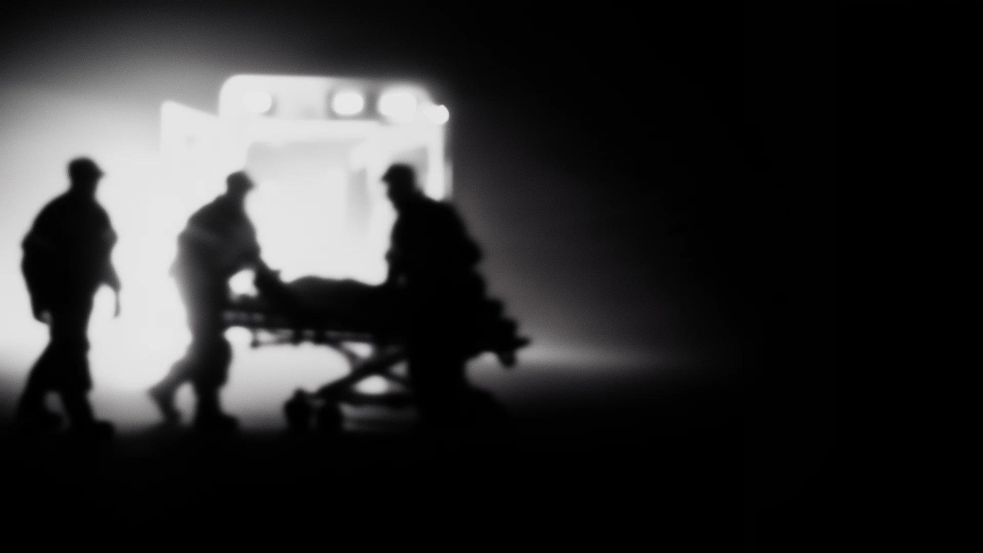 An emergency medical team moving a patient on a stretcher toward an ambulance.